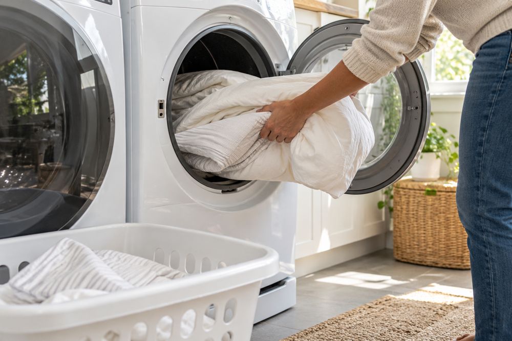 Bedding and pillowcases going into a front-loading clothes dryer, part of bed bug prep